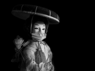 Mustavalkoinen kuva geisha-nukesta, jolla kasvomaski